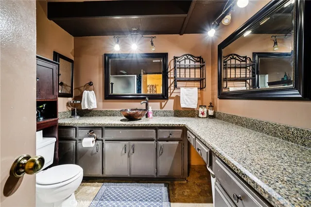 a spacious bathroom with a granite countertop sink a toilet and a large mirror