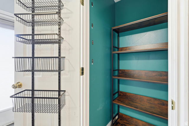 338 South 370 West Logan, UT 84321 - Photo 7 of 33 Interior storage area featuring a vivid teal wall, a four-tier wood-finish shelving unit, and an organizing system with multiple wire baskets