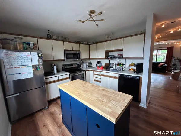 a kitchen with kitchen island a sink a stove a refrigerator cabinets and wooden floor
