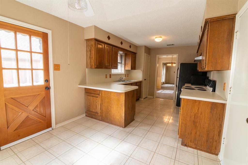 2028 Falcon Ridge Drive, Unit B Carrollton, TX 75010 - Photo 9 of 11 Kitchen with wood finish cabinets, light countertops, electric range, a peninsula, and black microwave