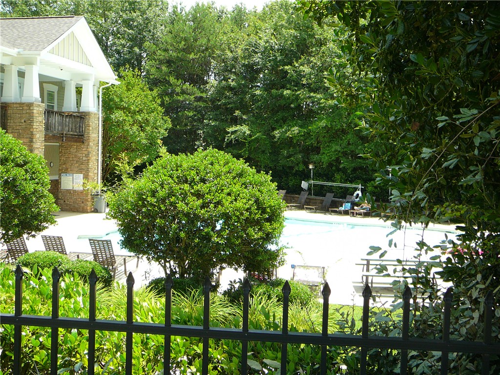 131 Lookover Drive Anderson, SC 29621 - Photo 4 of 18 A refreshing outdoor pool awaits, nestled beside a charming stone-faced building amidst lush greenery.