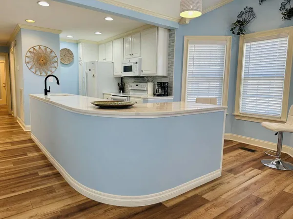 a view of kitchen with kitchen island a sink wooden floor and a large window