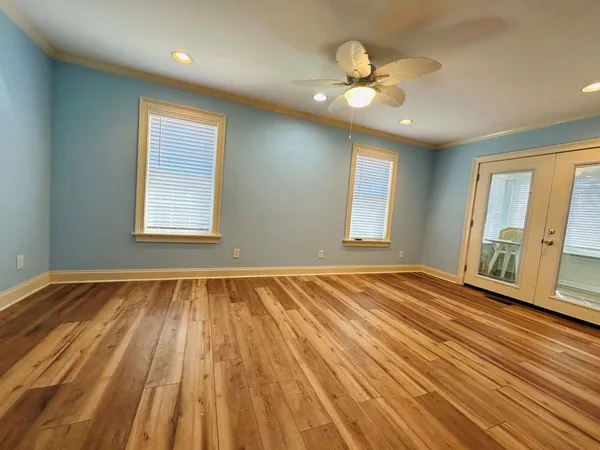 a view of an empty room with wooden floor and a window