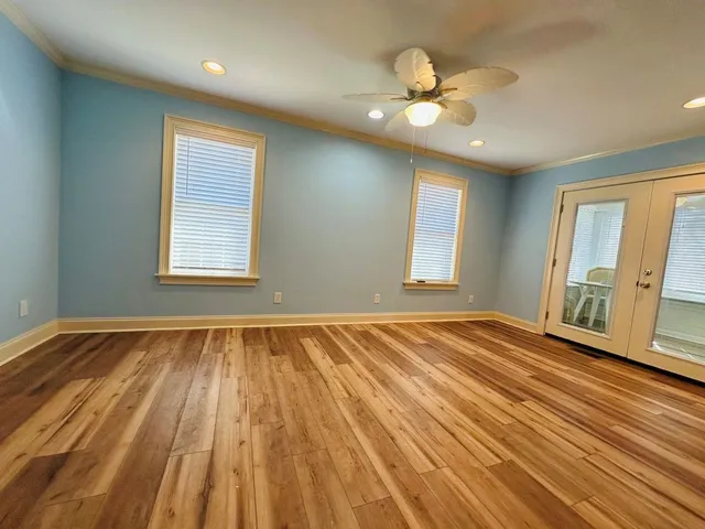 a view of an empty room with wooden floor and a window