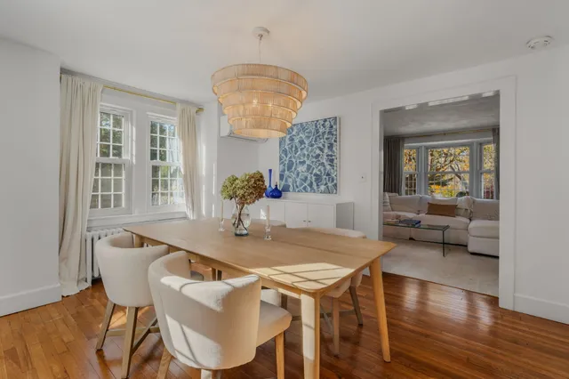 a dining room with wooden floor a chandelier a wooden table and chairs