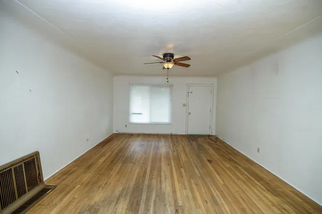 a view of a room with wooden floor and ceiling fan