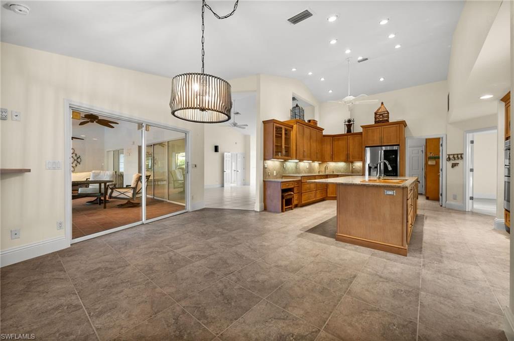 544 Roma Court Naples, FL 34110 - Photo 15 of 41 a view of a kitchen with stainless steel appliances granite countertop living room and couches with wooden floor