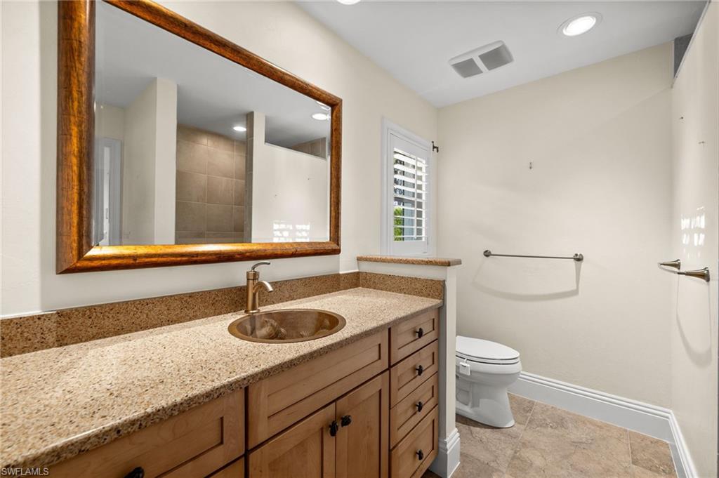 544 Roma Court Naples, FL 34110 - Photo 31 of 41 a bathroom with a granite countertop sink a toilet and mirror