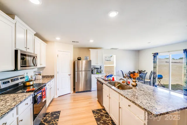 a kitchen with stainless steel appliances granite countertop a refrigerator and a sink