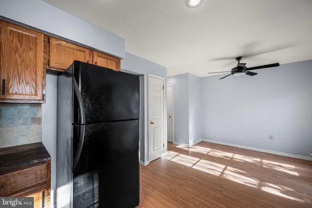 a kitchen with stainless steel appliances granite countertop a sink a stove a refrigerator wooden floor and a window