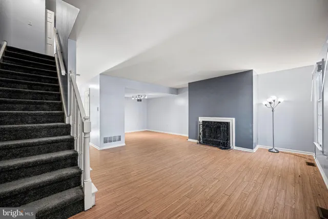 a view of an empty room with wooden floor fireplace and windows