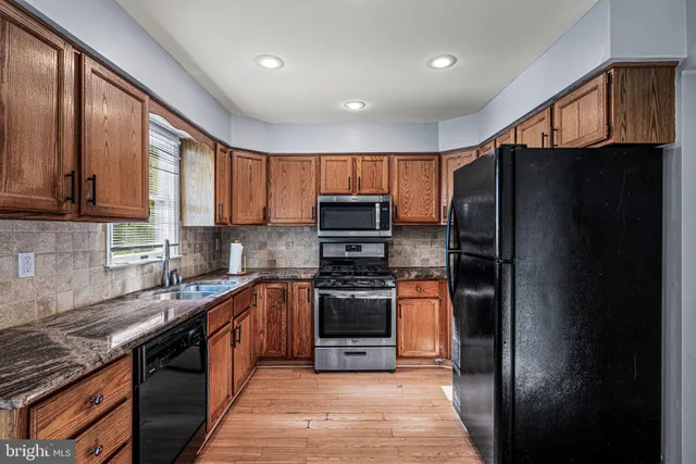 a view of a refrigerator in kitchen and an empty room with wooden floor