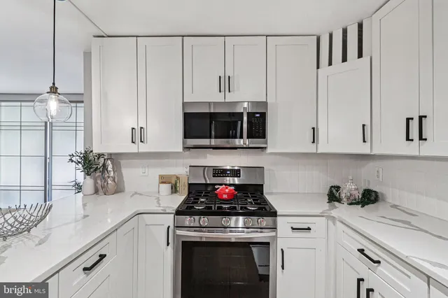 a kitchen with granite countertop white cabinets and stainless steel appliances