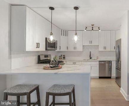 4620 North Park Avenue, Unit 1109E Chevy Chase, MD 20815 - Photo 4 of 5 a kitchen with stainless steel appliances granite countertop a sink a stove a refrigerator and white cabinets with wooden floor