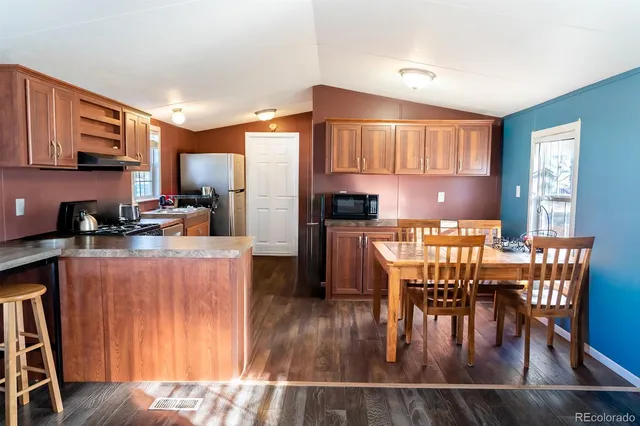 a kitchen with stainless steel appliances wooden floors wooden table and chairs