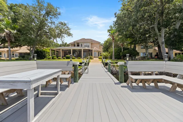 a view of a patio with couches and table and chairs with wooden floor and fence