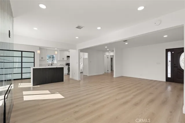 a view of an empty room with wooden floor and windows