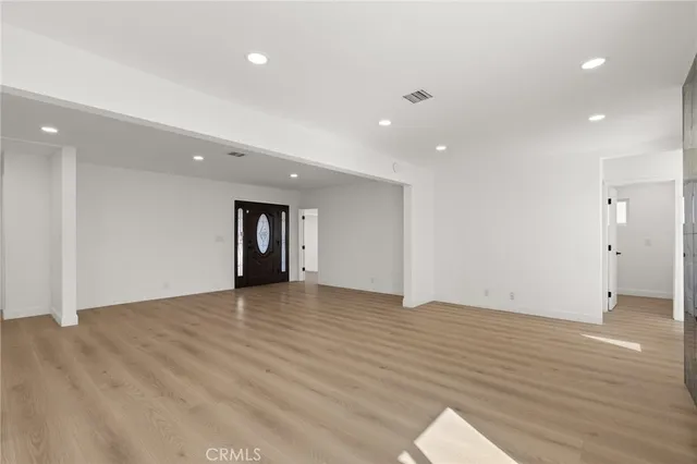 a view of an empty room with wooden floor and closet