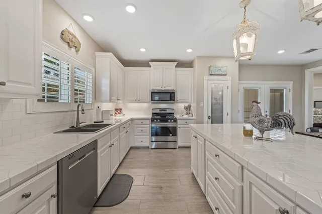 a large kitchen with stainless steel appliances granite countertop a sink and cabinets