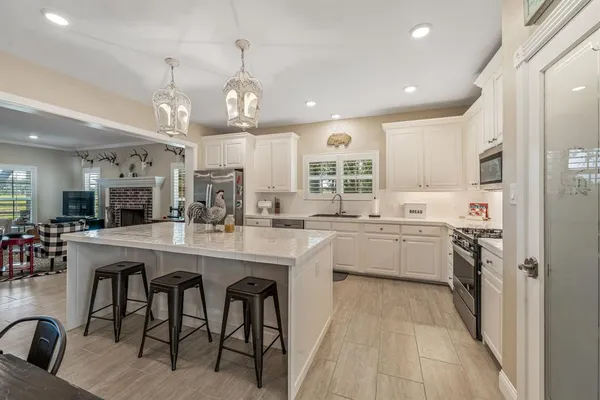 a kitchen with stainless steel appliances granite countertop a sink dishwasher a stove a refrigerator and island with wooden floor