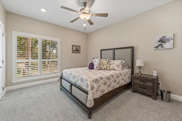a spacious bedroom with a bed a dresser and a chandelier