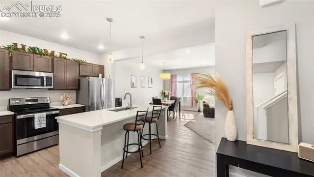 a kitchen with stainless steel appliances a table chairs refrigerator and microwave