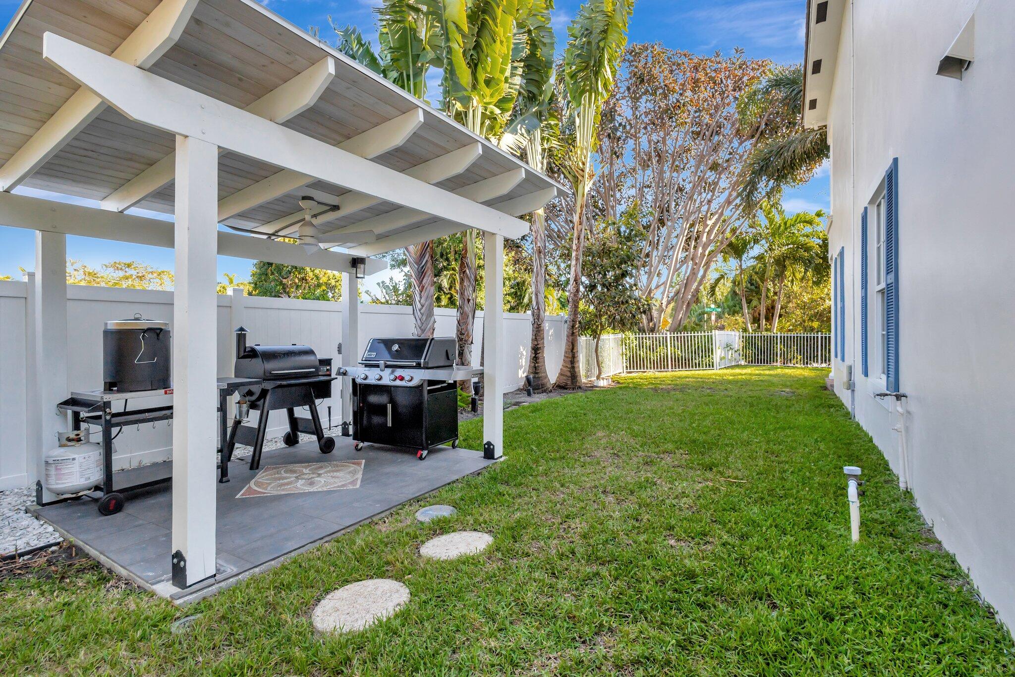 213 Kings Lynn Delray Beach, FL 33444 - Photo 16 of 39 a view of a backyard with table and chairs potted plants and large tree