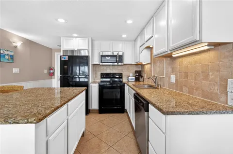 a kitchen with granite countertop a sink a counter top stainless steel appliances and cabinets