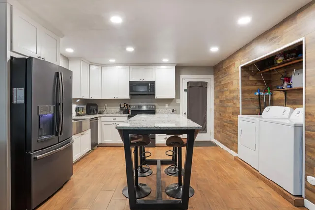 a kitchen with stainless steel appliances kitchen island granite countertop a refrigerator a stove a microwave oven a sink with island and chairs