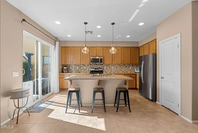 a kitchen with stainless steel appliances kitchen island granite countertop a refrigerator and a dining table