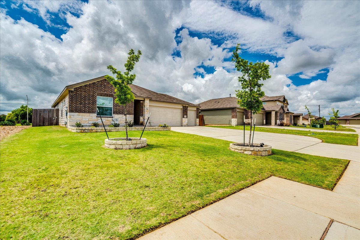 389 Salt Springs Road Kyle, TX 78640 - Photo 4 of 30 A well-maintained lawn welcomes you to this attractive brick and stone home with an attached garage.
