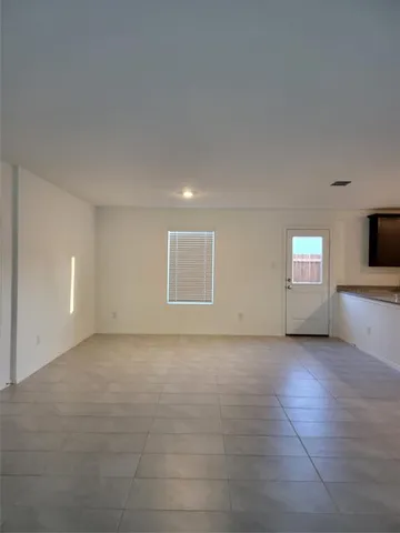 a view of an empty room with a window and a kitchen