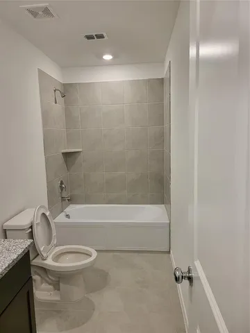 a bathroom with a granite countertop bathtub shower sink mirror and toilet