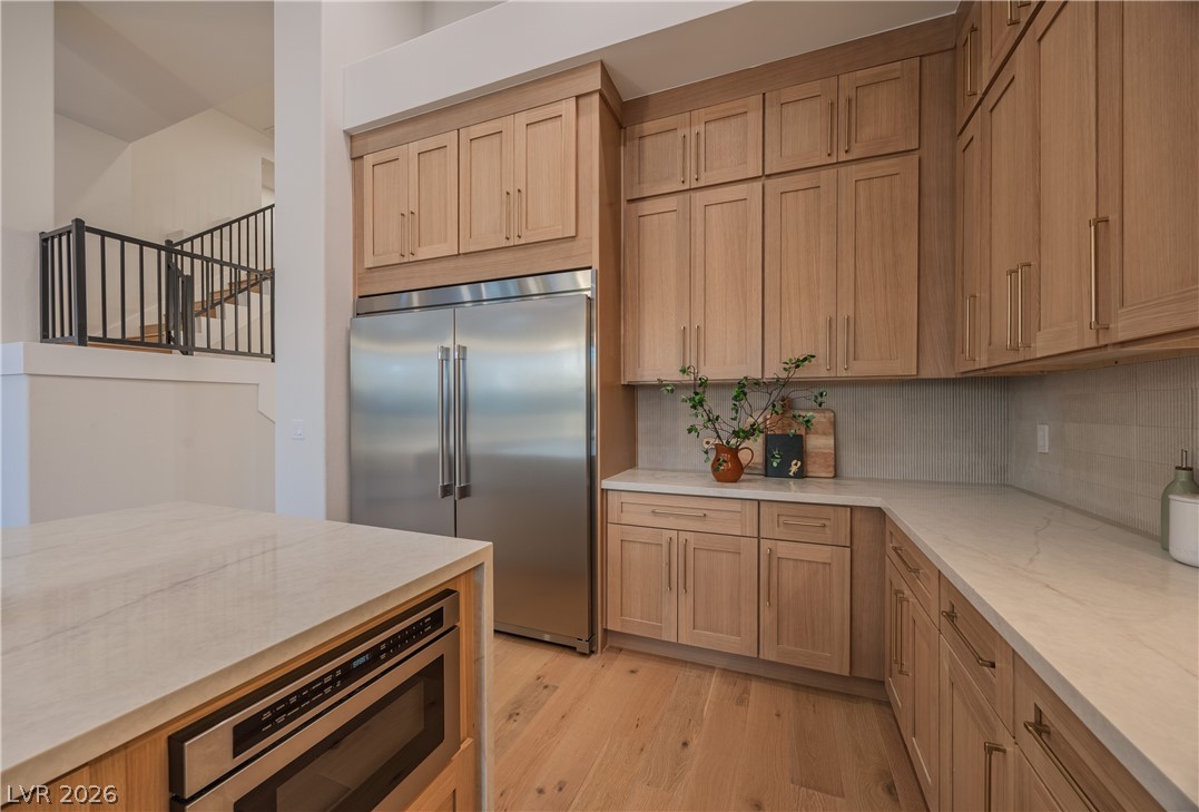 8800 Lusso Las Vegas, NV 89134 - Photo 35 of 85 Kitchen featuring built in appliances, light wood finished floors, decorative backsplash, light stone countertops, and light wood finish cabinetry