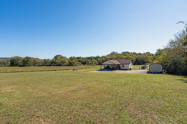 a white house with a swimming pool and large trees