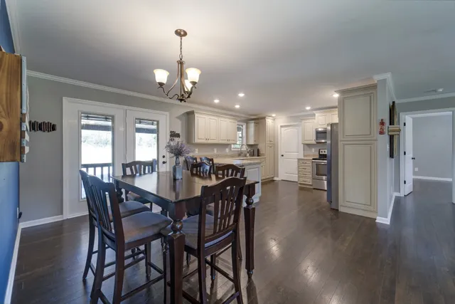 a view of a dining room and livingroom with furniture wooden floor a chandelier