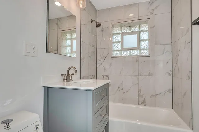 a bathroom with a bathtub shower sink vanity and toilet
