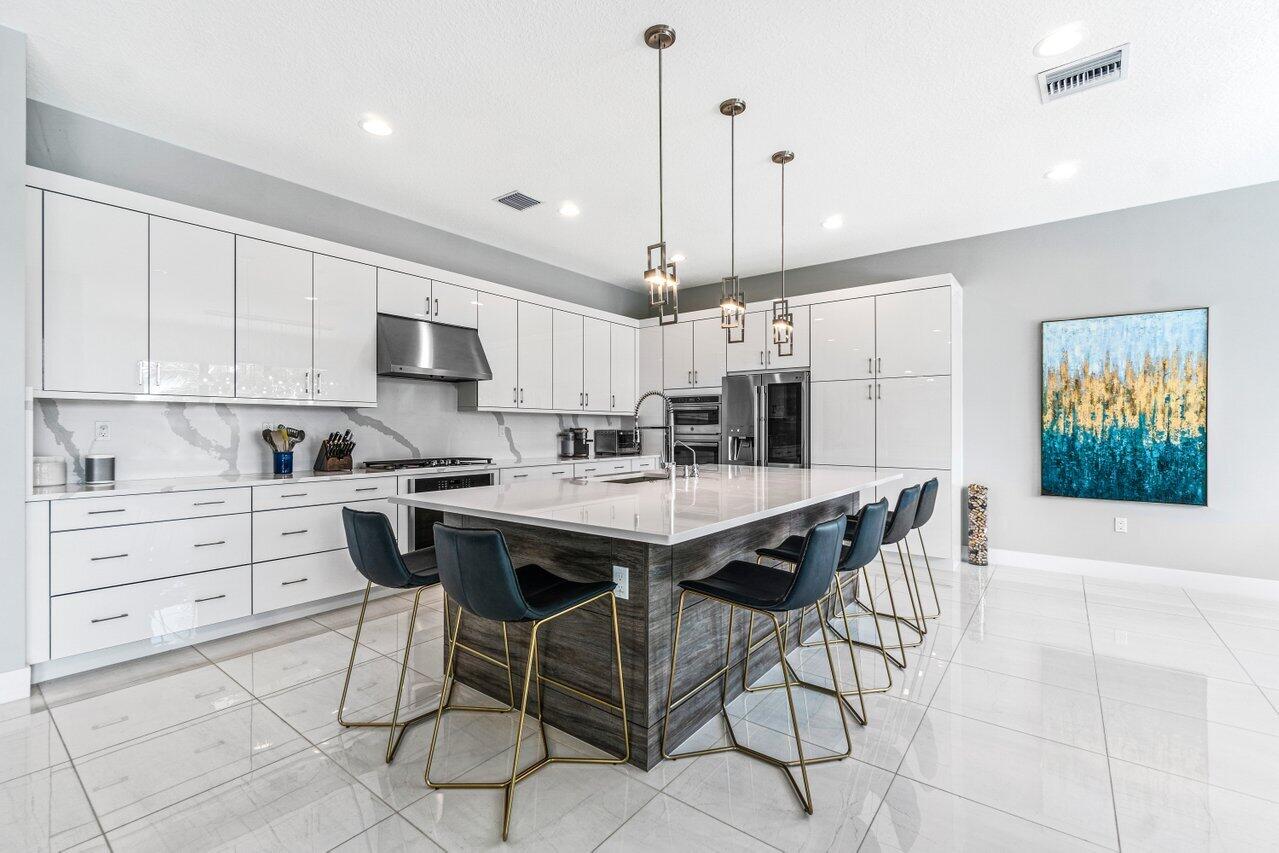 8618 Tower Bridge Court Boca Raton, FL 33496 - Photo 11 of 47 a kitchen with stainless steel appliances kitchen island granite countertop a sink a stove a dining table and chairs
