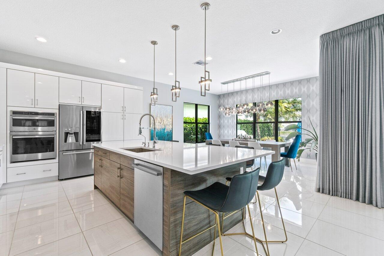 8618 Tower Bridge Court Boca Raton, FL 33496 - Photo 10 of 47 a kitchen with stainless steel appliances a table chairs sink and stove top oven