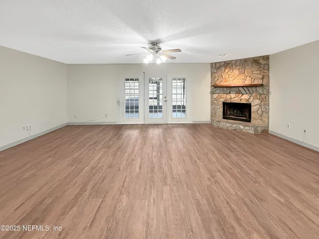 a view of an empty room with wooden floor fireplace and a window