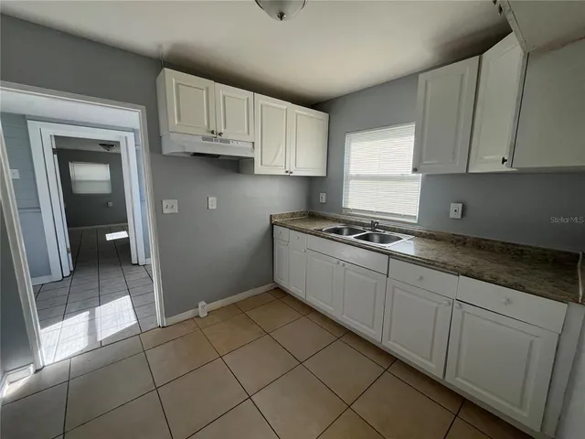 a kitchen with granite countertop a sink a stove and cabinets
