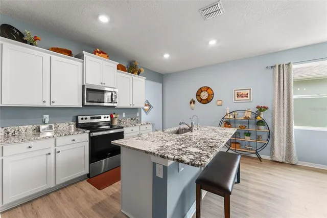 a kitchen with granite countertop white cabinets and stainless steel appliances