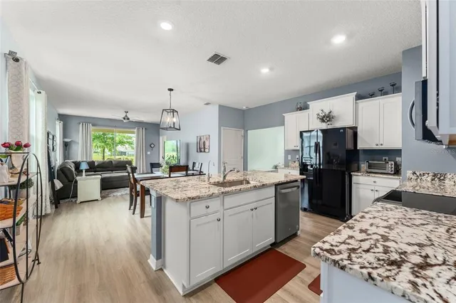 a kitchen with stainless steel appliances kitchen island granite countertop a sink stove and refrigerator