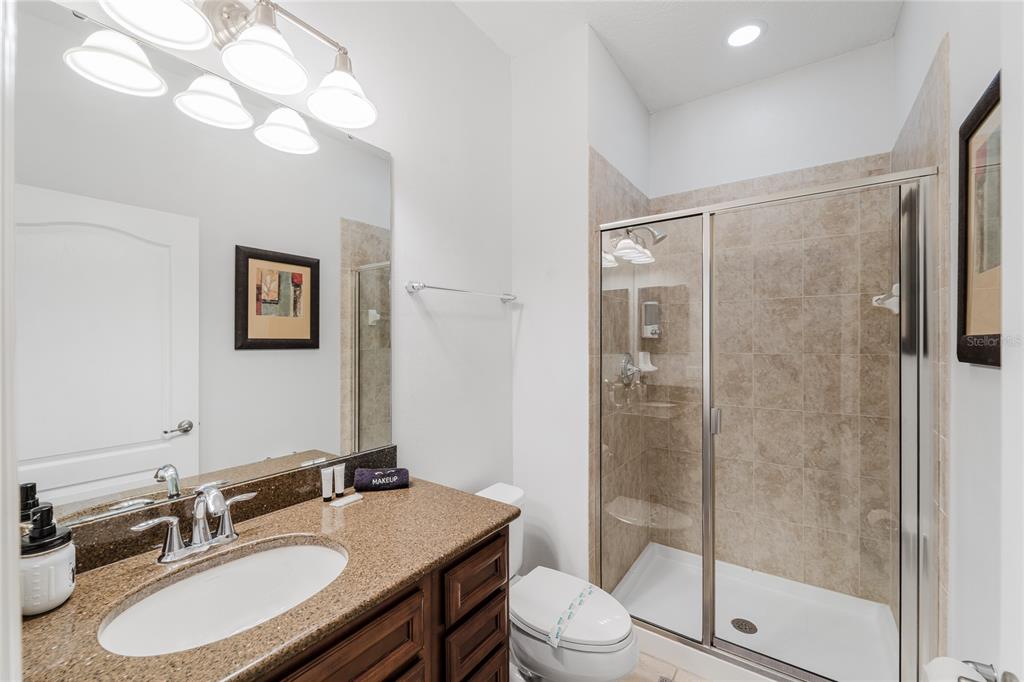 8961 Majesty Palm Road Kissimmee, FL 34747 - Photo 3 of 40 a bathroom with a granite countertop sink toilet a mirror a glass door and shower