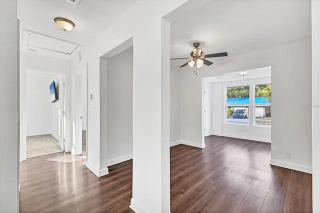 a view of an empty room with wooden floor and a ceiling fan