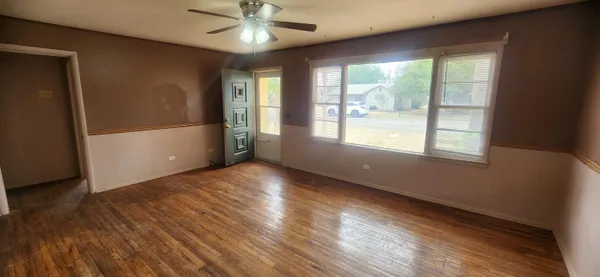a view of an empty room with a window and wooden floor