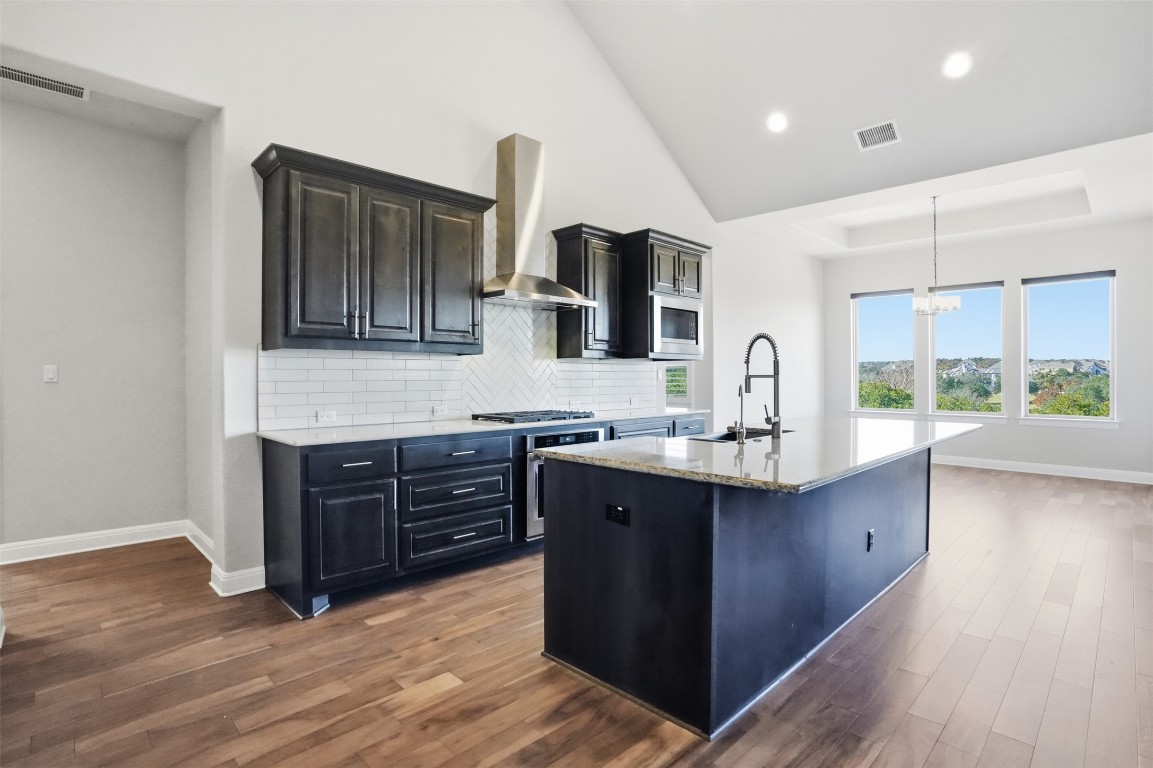 1441 River Vista Road Georgetown, TX 78628 - Photo 15 of 37 Kitchen featuring a center island with sink, light stone counters, dark wood-style flooring, hanging light fixtures, and recessed lighting