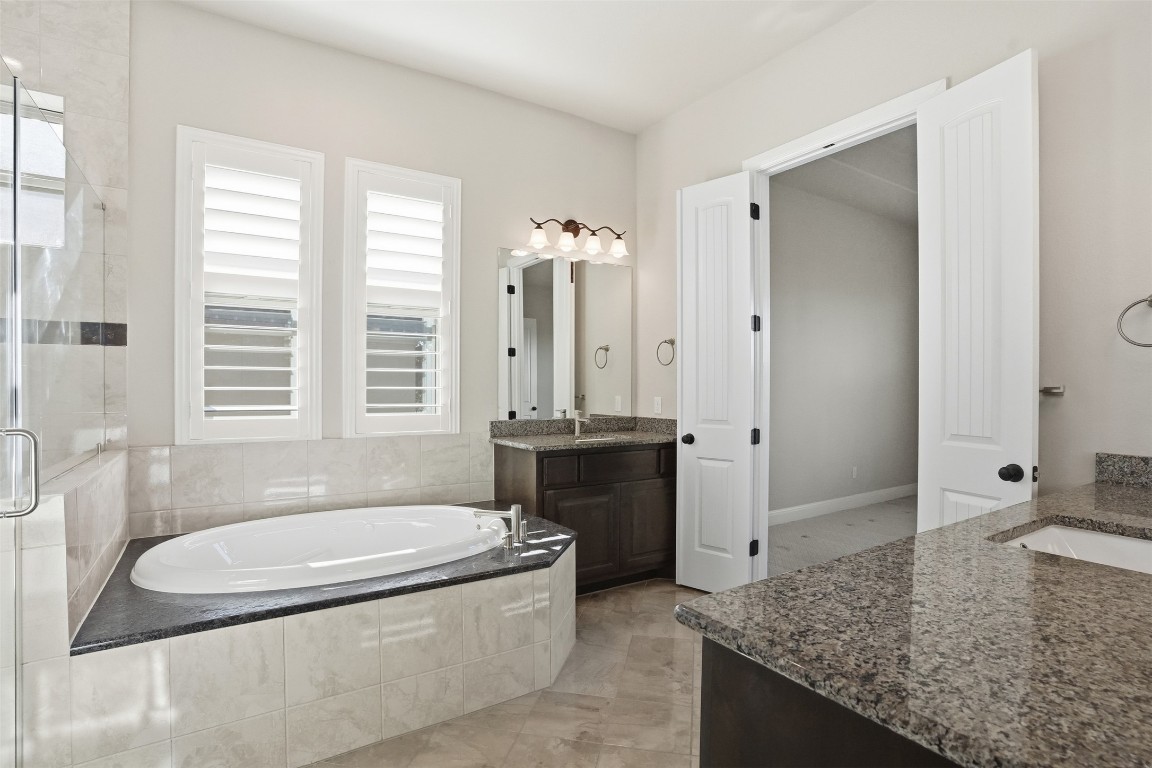 1441 River Vista Road Georgetown, TX 78628 - Photo 24 of 37 Bathroom with two vanities, a garden tub, and a shower stall