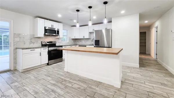a kitchen with stainless steel appliances granite countertop a stove top oven a refrigerator a sink and a oven