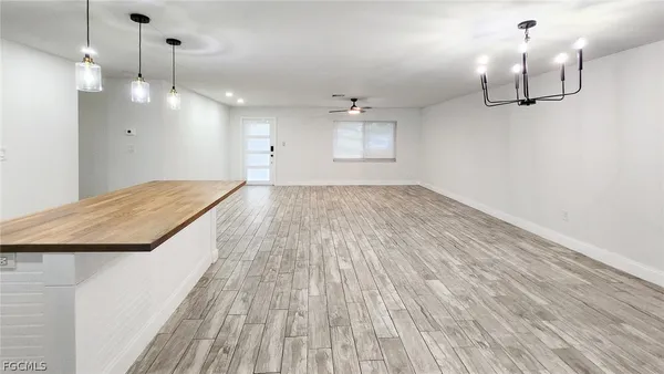 a view of empty room with wooden floor and kitchen view
